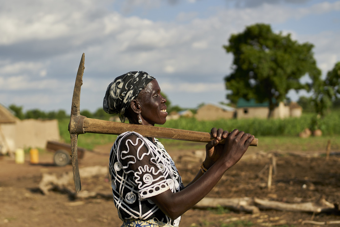 Ghanaian farmer walking with tool