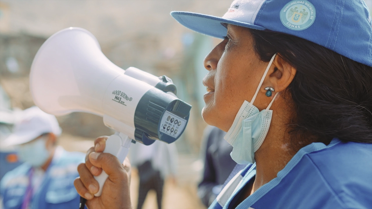 Close up of a woman wearing a blue baseball cap speaking into a megaphone